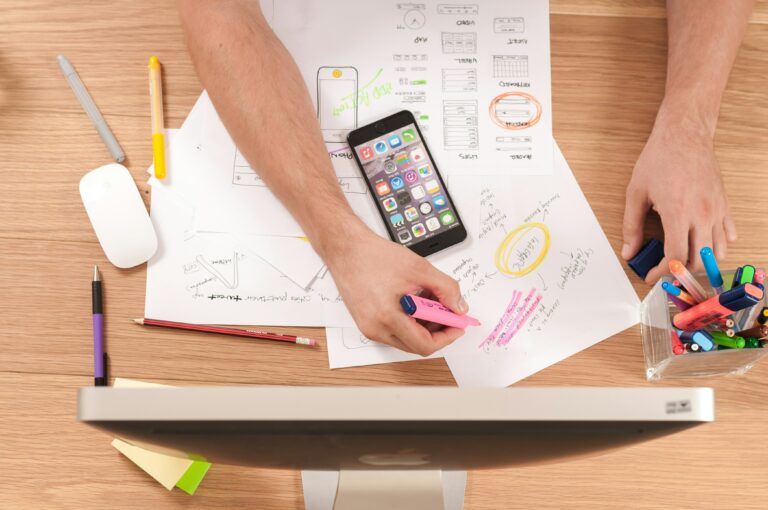 A workspace on a wooden desk with a lot of notes. Someone is writing on the notes on the desk. Content marketing for SaaS is a lot of work and requires a lot of research and preparation.